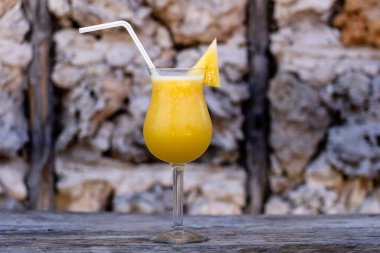 Freshly squeezed juice from pineapple in a glass goblet on the background of an old stone wall. Island of Zanzibar, Tanzania, East Africa. Close up, copy space
