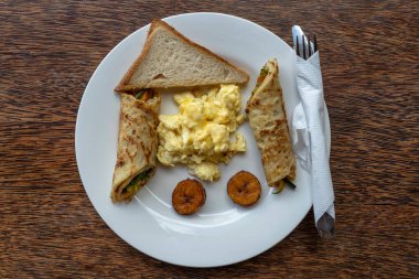 Otelin restoranında çırpılmış yumurta ve sarılmış muzlu gözlemelerden oluşan tropik bir kahvaltı. Zanzibar adası, Tanzanya, Afrika, kapatın. Üst görünüm