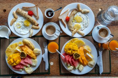 Tropical breakfast of fruit, coffee and scrambled eggs and banana pancake for two on the beach near sea in hotel restaurant, island Zanzibar, Tanzania, Africa, close up, top view