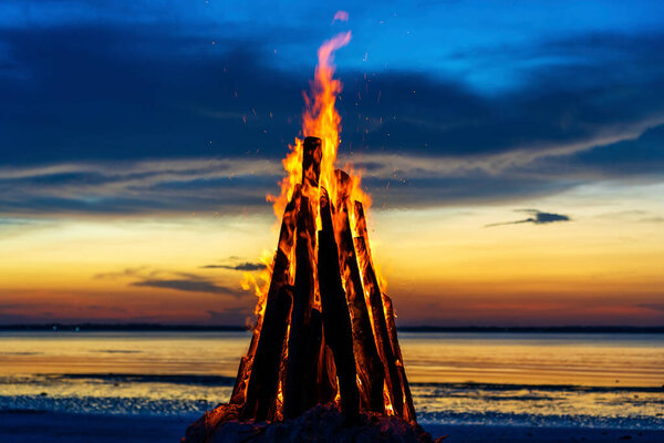 The big fire burns against the background of the night sky near sea on the island of Zanzibar, Tanzania, East Africa, close up. Bright flame. A bonfire in the evening.