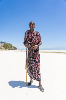 Zanzibar, Tanzanya - 28 Ekim 2019: Geleneksel giysiler içinde Afrikalı adam masai okyanus kenarında, Tanzanya, Doğu Afrika 'daki Zanzibar adasının kumsalında duruyor.