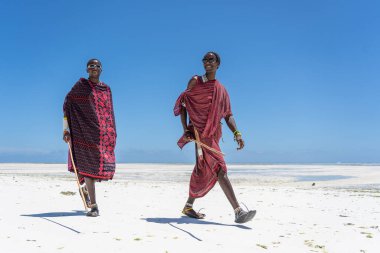 Zanzibar, Tanzanya - 28 Ekim 2019: Geleneksel giysiler giymiş iki Afrikalı adam, Doğu Afrika 'daki Tanzanya' daki Zanzibar adasının kumsalında okyanus kenarında duruyor.
