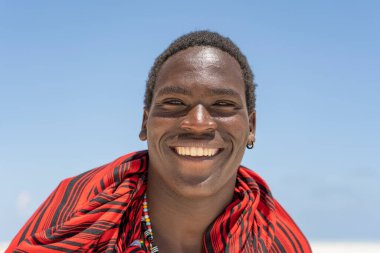 Zanzibar, Tanzanya - 11 Kasım 2019: Afrikalı adam geleneksel giysiler içinde okyanus kenarında, Tanzanya, Doğu Afrika 'daki Zanzibar adasının kumsalında duruyor.