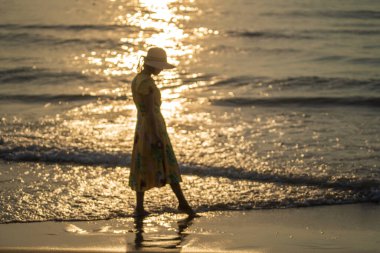 Genç Asyalı bir kızın tropikal sahildeki bulanık görüntüsü. Sabah vakti deniz suyuyla kaplı. Gün doğumunda, Vietnam 'da..