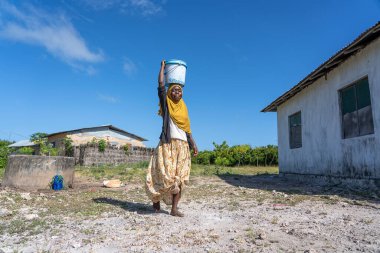 Zanzibar, Tanzanya - 14 Ocak 2020: Tanzanya, Doğu Afrika 'daki Zanzibar Adası' nda bir sokakta tanımlanamayan Afrikalı kız ve kova