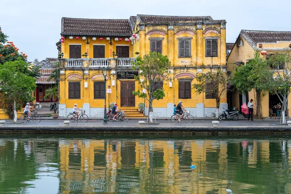 ホイアン ベトナム 2020年3月16日 ヨーロッパの観光客はホイアン ベトナムの古い黄色の壁の背景を背景に 旧市街の川の近くの道路に自転車に乗る — ストック写真