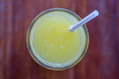 Bir bardak portakal suyu, ahşap arka planda saman içmek, üst manzara, kapat.