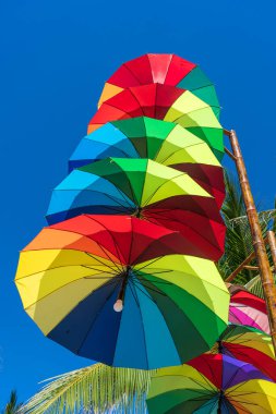 Sokak lambaları renkli şemsiyelerle süslenir. Güneşli bir günde, Vietnam 'da, mavi gökyüzüne karşı bir sütuna asılır.