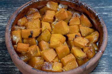 Ballı fırında sarı balkabağı, zeytinyağı ve ahşap masadaki baharatlar. Vejetaryen yemeği. Kapat.