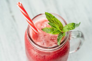 Beyaz masadaki cam bardakta taze organik kırmızı smoothie, yakın çekim. Yaz meyvelerini tazeliyorum. Sağlıklı beslenme kavramı. Güneşli bir günde kızılcık ve ahududu püresi.