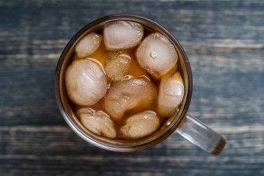 Ahşap arka planda buzlu siyah çay manzarası. Bardakta buzlu siyah çay, yaklaşın.