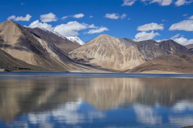 Hintli Himalayalar, Ladakh Bölgesi, Jammu ve Kashmir 'de mavi gökyüzüne ve Pangong Gölü' ne bakan görkemli kayalık dağların manzarası. Doğa ve seyahat kavramı