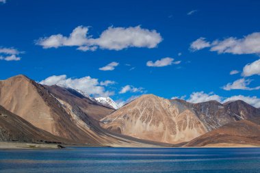 Hintli Himalayalar, Ladakh Bölgesi, Jammu ve Kashmir 'de mavi gökyüzüne ve Pangong Gölü' ne bakan görkemli kayalık dağların manzarası. Doğa ve seyahat kavramı