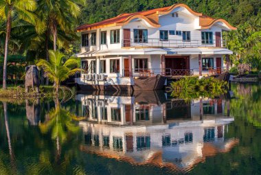 Tropikal bir ev, yeşil palmiye ağaçlarının olduğu ormanda, denizin yanındaki büyük bir gölde bir gemi şeklinde. Tayland 'da lüks bir sahil beldesinde. Doğa ve seyahat kavramı