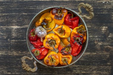 Fırınlanmış kırmızı ve sarı dolmalık biber. Biberler ahşap bir masada fırın kabında. Sağlıklı ve lezzetli bir vejetaryen yemeği. Kapat, üst görünüm