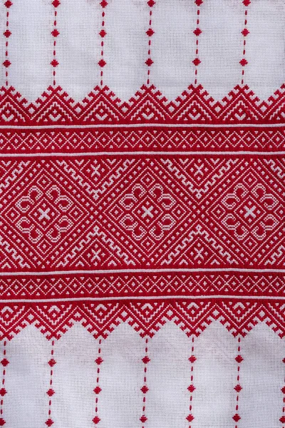 Detail of embroidered ornament with red threads on white fabric, ukrainian folk embroidery, close up. National clothes of Ukraine