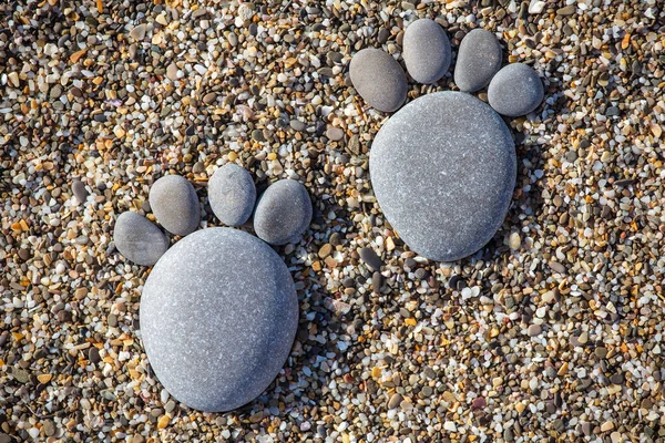 Two tiny stone feet and toes on pebble stone background, stone in the shape of a human feet. Closeup