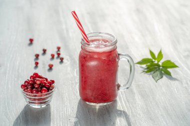 Beyaz masadaki cam bardakta taze organik kırmızı smoothie, yakın çekim. Yaz meyvelerini tazeliyorum. Sağlıklı beslenme kavramı. Güneşli bir günde kızılcık ve ahududu püresi.