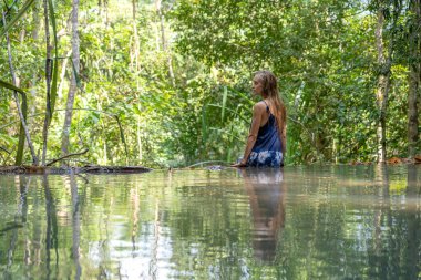 Tayland 'ın Koh Phangan adasında, tropikal yağmur ormanlarında çağlayan şelale sularının yanında genç bir kadın.