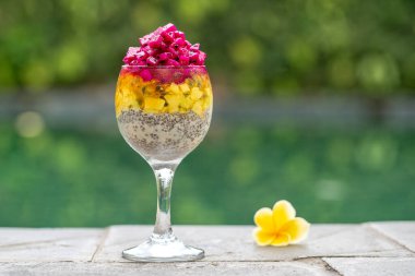 Kırmızı ejderha meyveli Chia tohumu pudingi, çarkıfelek meyvesi, mango ve avokado kahvaltıda yüzme havuzu suyunun arka planında, yakın çekim. Sağlıklı beslenme kavramı.