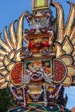 Endonezya 'nın Bali Adası' ndaki merkez caddede geleneksel iblis ve çiçek heykelleri bulunan Bade yakma kulesi. Yaklaşan yakma töreni için hazır. Kapat.