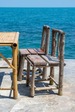 Bambu masası ve tropikal sahildeki deniz suyunun yanındaki boş kafede tahta sandalyeler. Kapatın. Koh Phangan Adası, Tayland