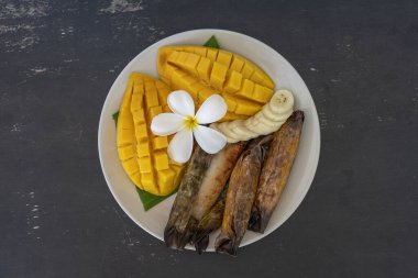 Tayland usulü tatlı, sarı mangolu ve palmiye yapraklı muzlu pilav. Sarı mango ve yapışkan pirinç Tayland 'ın popüler geleneksel yemeğidir. Kapat.