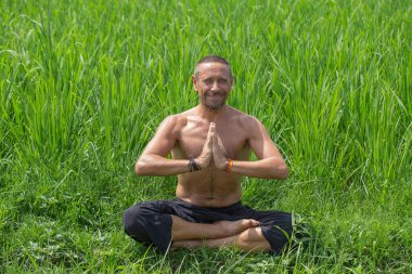 Adam Endonezya 'nın Bali adasındaki yeşil pirinç tarlasının yakınında yoga yapıyor ve meditasyon yapıyor. Kapatın. Sağlıklı yaşam tarzı kavramı