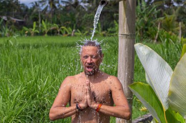 Yoga yapan ve meditasyon yapan adam Endonezya 'nın Bali adasındaki su akıntısının altında pozisyon aldı. Kapatın. Sağlıklı yaşam tarzı kavramı