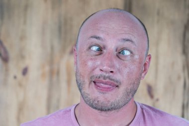 Yakışıklı, beyaz, kel adam komik surat yapıyor. Yaklaş. İnsanlar ve yaşam tarzı konsepti. İçerde orta yaşlı bir adamın portresi. Yüz ifadesi, duygular