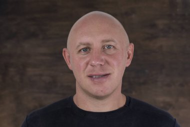 Kameraya bakan orta yaşlı, beyaz, kel bir adamın yakın çekimi. İnsanlar ve yaşam tarzı konsepti. İçerde orta yaşlı bir adamın portresi