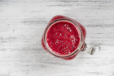Beyaz masada cam bardakta taze organik kırmızı smoothie, yakın plan, üst manzara. Yaz meyvelerini tazeliyorum. Sağlıklı beslenme kavramı. Böğürtlen, ahududu ve çilekli smoothie