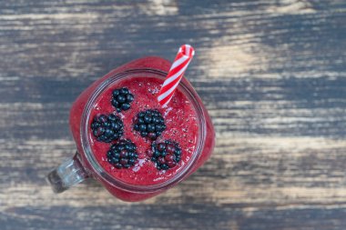 Beyaz masada cam bardakta taze organik kırmızı smoothie, yakın plan, üst manzara. Yaz meyvelerini tazeliyorum. Sağlıklı beslenme kavramı. Böğürtlen, ahududu ve çilekli smoothie