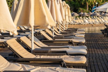 Boş güneşlik ve güneş şemsiyeleri sabah, deniz kenarında. Deniz kıyısındaki lüks oteldeki kumsal. Güzel bir sabah deniz manzarası. Bodrum, Türkiye