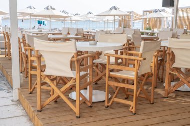 Yunanistan 'ın Kos Adası sahilindeki restoranda boş masa ve sandalyeler. Deniz kenarındaki sahil kafeteryasında, açık havada. Seyahat ve tatil kavramı