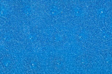 Mavi fayanslı yüzme havuzunda su dalgalanmaları. Güzel mavi yüzme havuzu su yüzeyi manzarası, üst manzara.