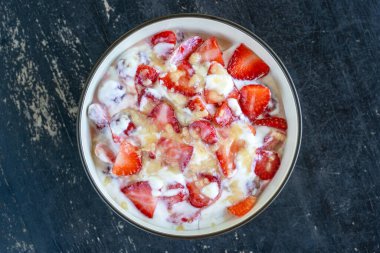 Kırmızı çilek ve beyaz yoğurt. Kahvaltıda meyveli tatlı ve mükemmel olgunlukta çilek, yakın çekim.