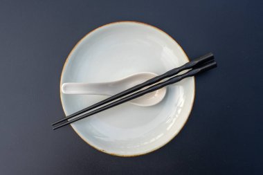 Asya lokantasında boş tabak, kaşık ve çubuklar siyah masada, yakın plan, üst manzara. Tablo ayarı