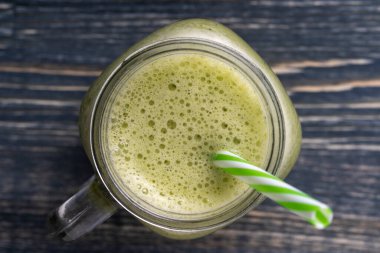 Avokado, kivi, muz, bal, dereotu ve maydanozdan taze yeşil smoothie, ahşap arka planda cam bardak, yakın plan, üst manzara. Sağlıklı beslenme kavramı