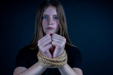Portrait of young girl with bound hands on black background. Close up clipart