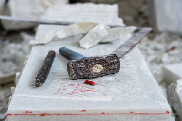 Sculptor tools on a marble slab, close up. Workplace, traditional tools sculptor, red chalk, ruler, hammer and chisel for working stone. Vietnam, Da Nang