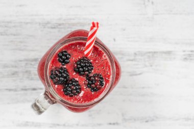 Beyaz masada cam bardakta taze organik kırmızı smoothie, yakın plan, üst manzara. Yaz meyvelerini tazeliyorum. Sağlıklı beslenme kavramı. Böğürtlen, ahududu ve çilekli smoothie