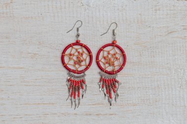 Ubud, Bali, Endonezya 'daki yerel sokak pazarında satılmak üzere beyaz ahşap arka planda bulunan kırmızı ev yapımı küpeler.