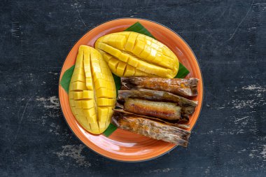 Tayland usulü tatlı, sarı mangolu ve palmiye yapraklı muzlu pilav. Sarı mango ve yapışkan pirinç Tayland 'ın popüler geleneksel yemeğidir. Kapat.