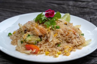 Kızarmış pirinç, karides ve sebzeyle birlikte eski ahşap bir masada beyaz bir tabakta, yakın çekim. Tayland yemeği, Tayland mutfağı. Restoranda kızarmış pilav ve deniz ürünleri.