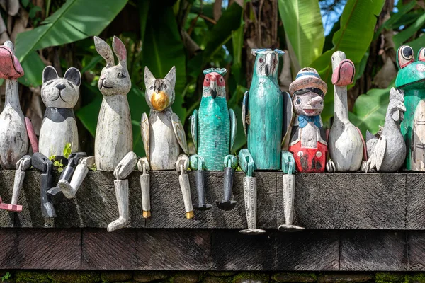 Old wooden souvenirs toys on the stone fence near the doll shop in Ubud, Bali island, Indonesia. Close up