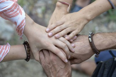 Birlik ve takım çalışması için kollar bir araya toplandı. Çemberin ortasında bir sürü el bir araya geliyor. Açık hava çekimini kapat. Birçok el doğaya bağlanıyor..