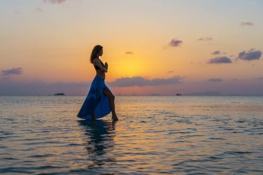 Gün batımında cennet adasındaki tropikal sahilde dans eden genç güzel kız, kapat. Yaz kavramı. Tatil seyahati.