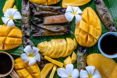Tayland usulü tatlı, sarı mangolu ve palmiye yapraklı muzlu pilav. Sarı mango ve yapışkan pirinç Tayland 'ın popüler geleneksel tatlısıdır. Kapat.