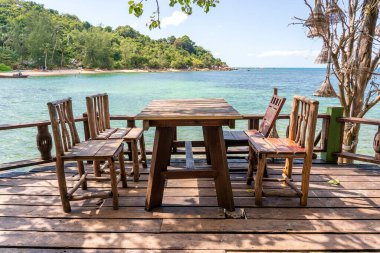 Ahşap masa ve deniz suyunun yanındaki boş sahil kafesinde sandalyeler. Kapatın. Koh Phangan Adası, Tayland